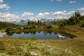 Two people mountain biking around a pond on a small mountain trail.